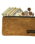 Tan waxed canvas zip pouch holding folded cash and coins on a white background