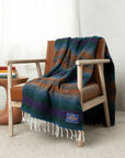 Teal, rust, blue and purple striped blanket draped over a wooden armchair