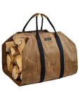 Tan waxed canvas firewood carrier with black webbing handles, loaded with split logs, on a white background
