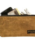 Tan waxed canvas zip pouch holding a phone, wallet and keys on a white background
