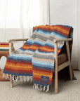 Light blue, orange and cream striped falsa blanket draped over a wooden armchair