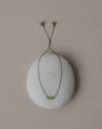 White stone with a green wire and small green flowers on a beige background