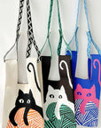 Three knit cat bags hanging from woven and braided straps