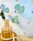 Bring a pop of color and artistry to your home with this handcrafted stained glass silver dollar eucalyptus stem by Samara Designs Studio. This stem is made from beautiful celadon green stained glass, carefully cut and assembled by hand to create a lasting botanical accent that will never wilt or fade.