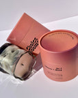 Smoky gray wavy glass candle beside an open pink box on white