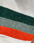 Close-up of green, sage and orange stripes woven into a cream blanket