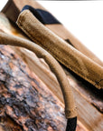 Close-up of the waxed canvas handle wraps resting on a log