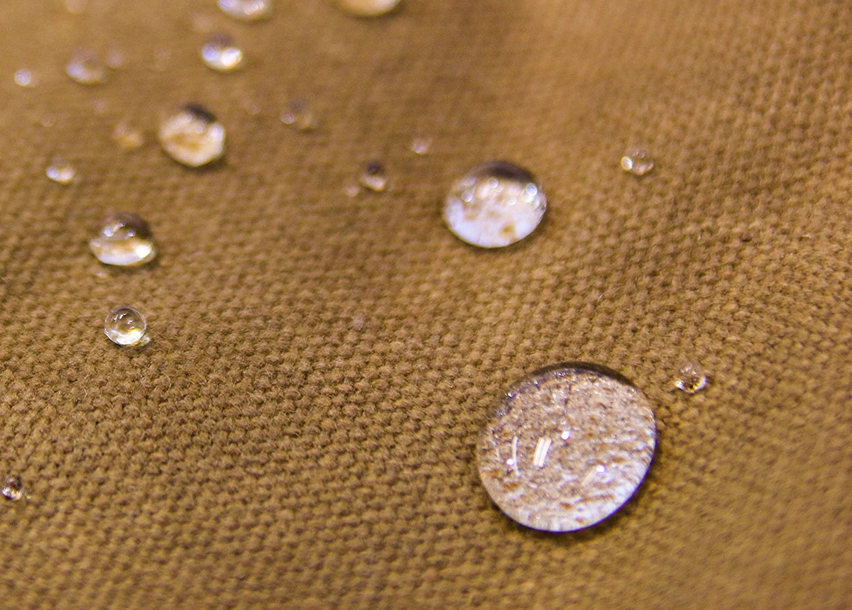 Close-up of water beading on tan waxed canvas
