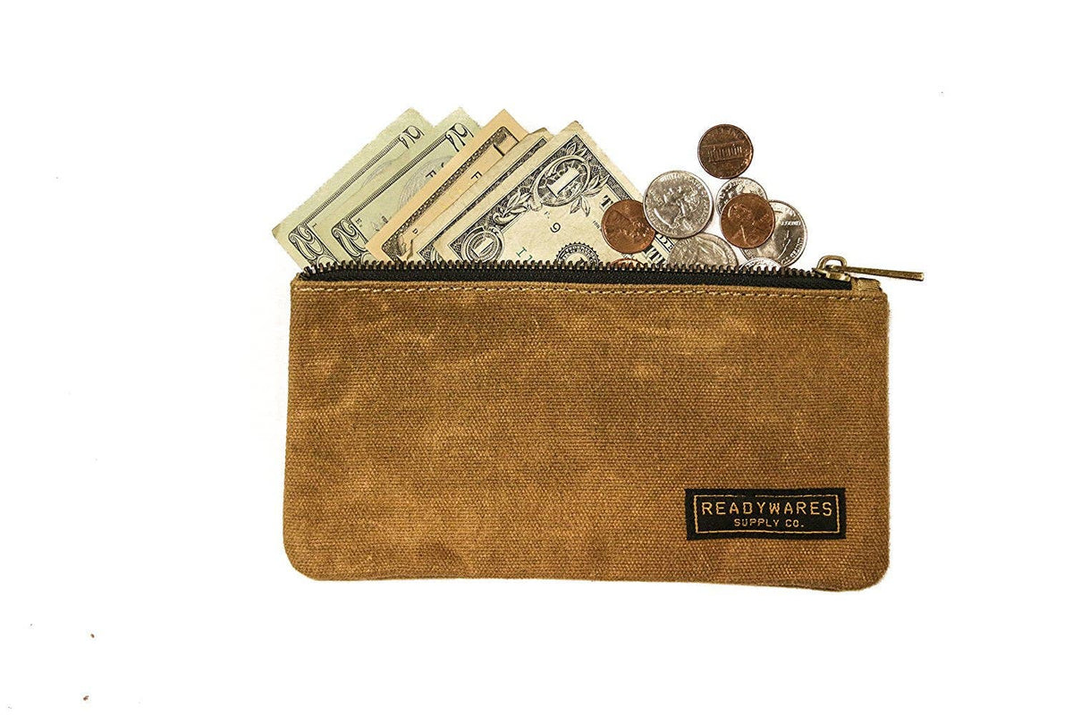 Tan waxed canvas zip pouch holding folded cash and coins on a white background