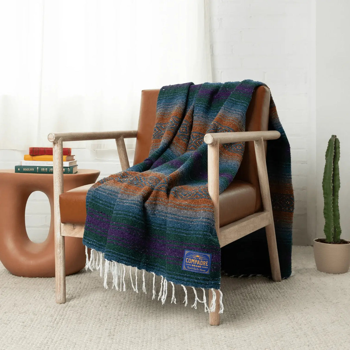 Teal, rust, blue and purple striped blanket draped over a wooden armchair