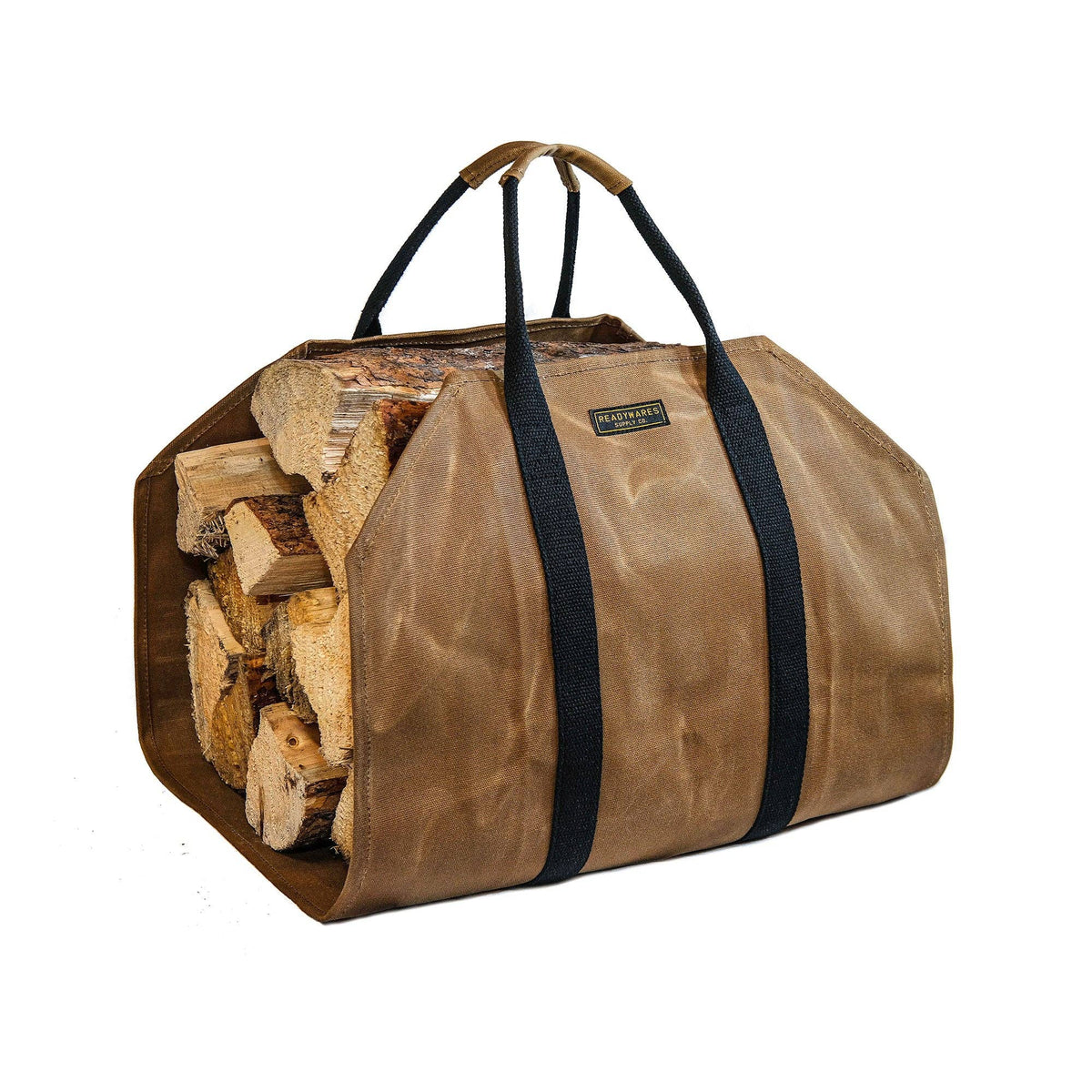 Tan waxed canvas firewood carrier with black webbing handles, loaded with split logs, on a white background