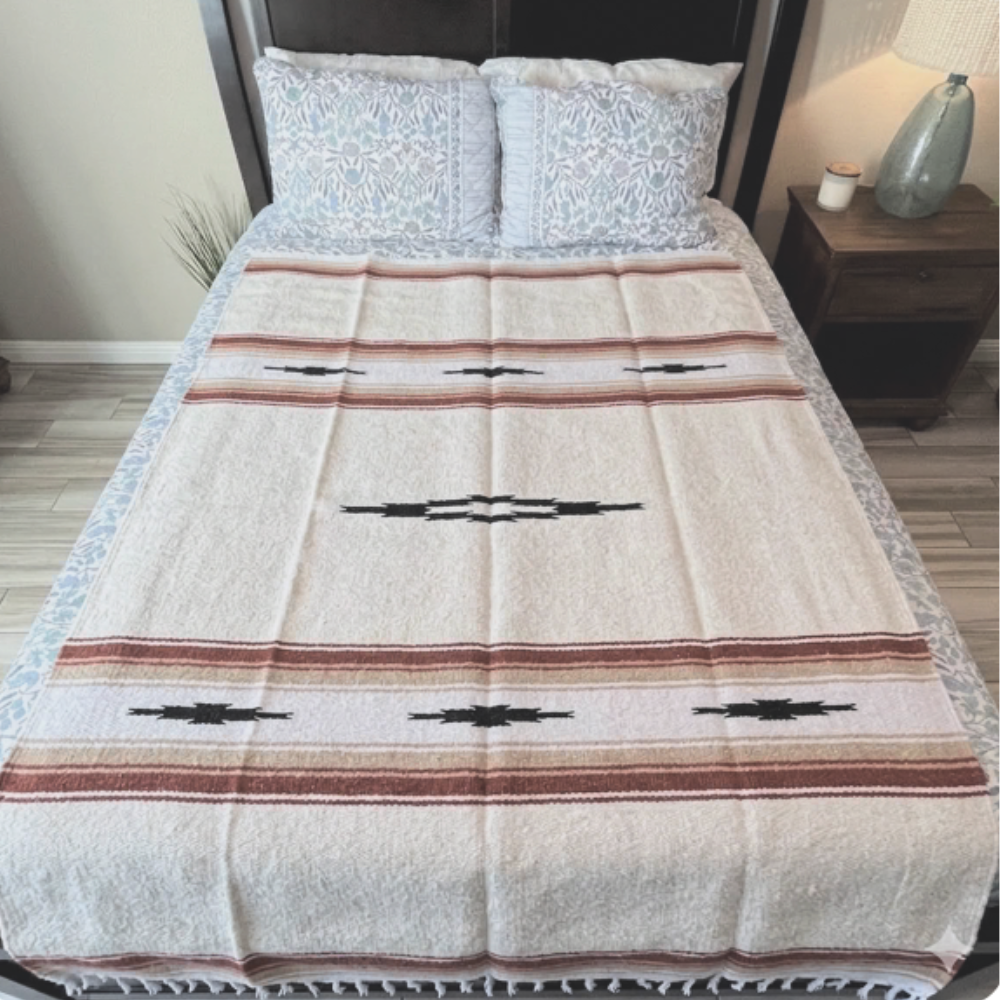 Cream Desert Mesa blanket with red stripes and black diamonds spread across a bed