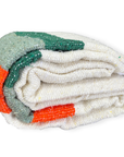 Cream Sea Breeze blanket with green and orange stripes rolled up on a white background