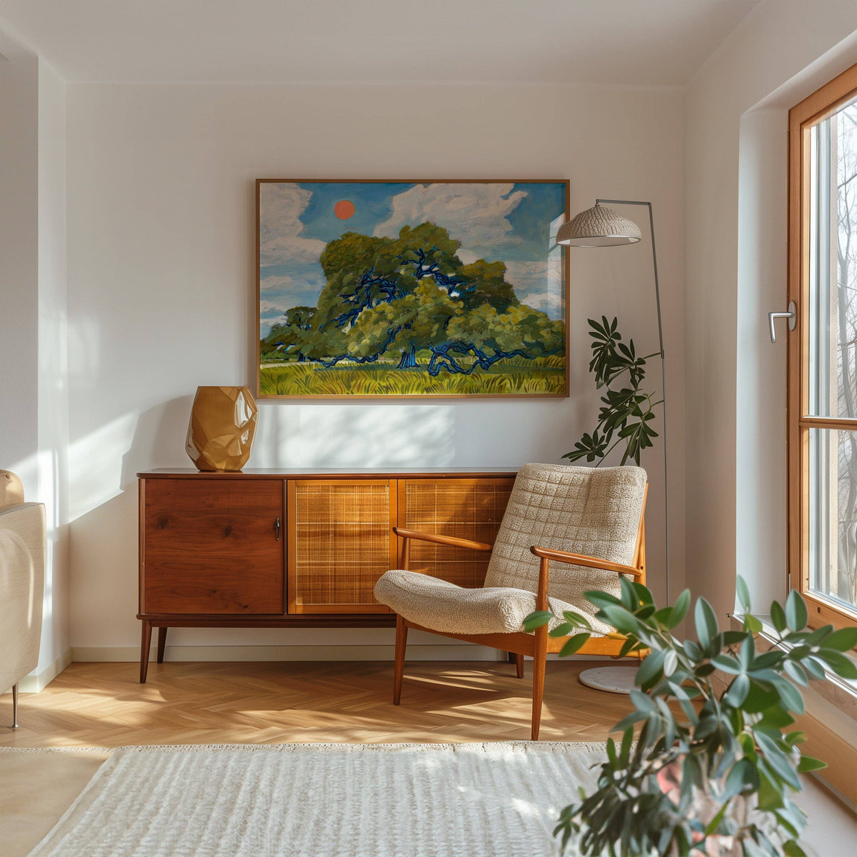Framed live oak print on a white wall above a wood sideboard and lounge chair