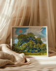 Framed live oak print resting on cream bedding with sheer curtains behind
