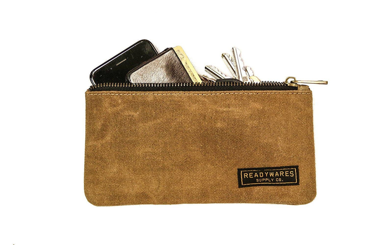 Tan waxed canvas zip pouch holding a phone, wallet and keys on a white background