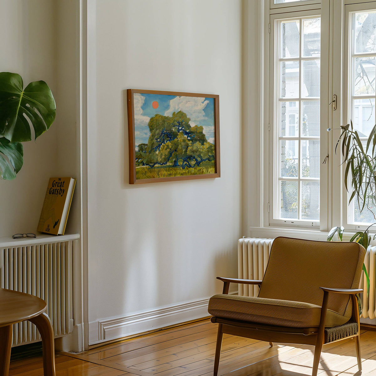 Small framed live oak print on a white wall above a mustard armchair by a window