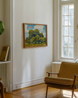 Small framed live oak print on a white wall above a mustard armchair by a window