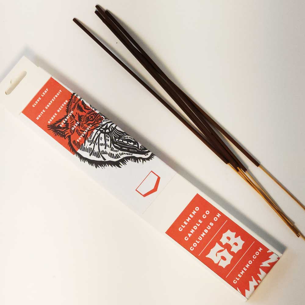 Back of a Clemeno White Tiger incense box with incense sticks on a white surface
