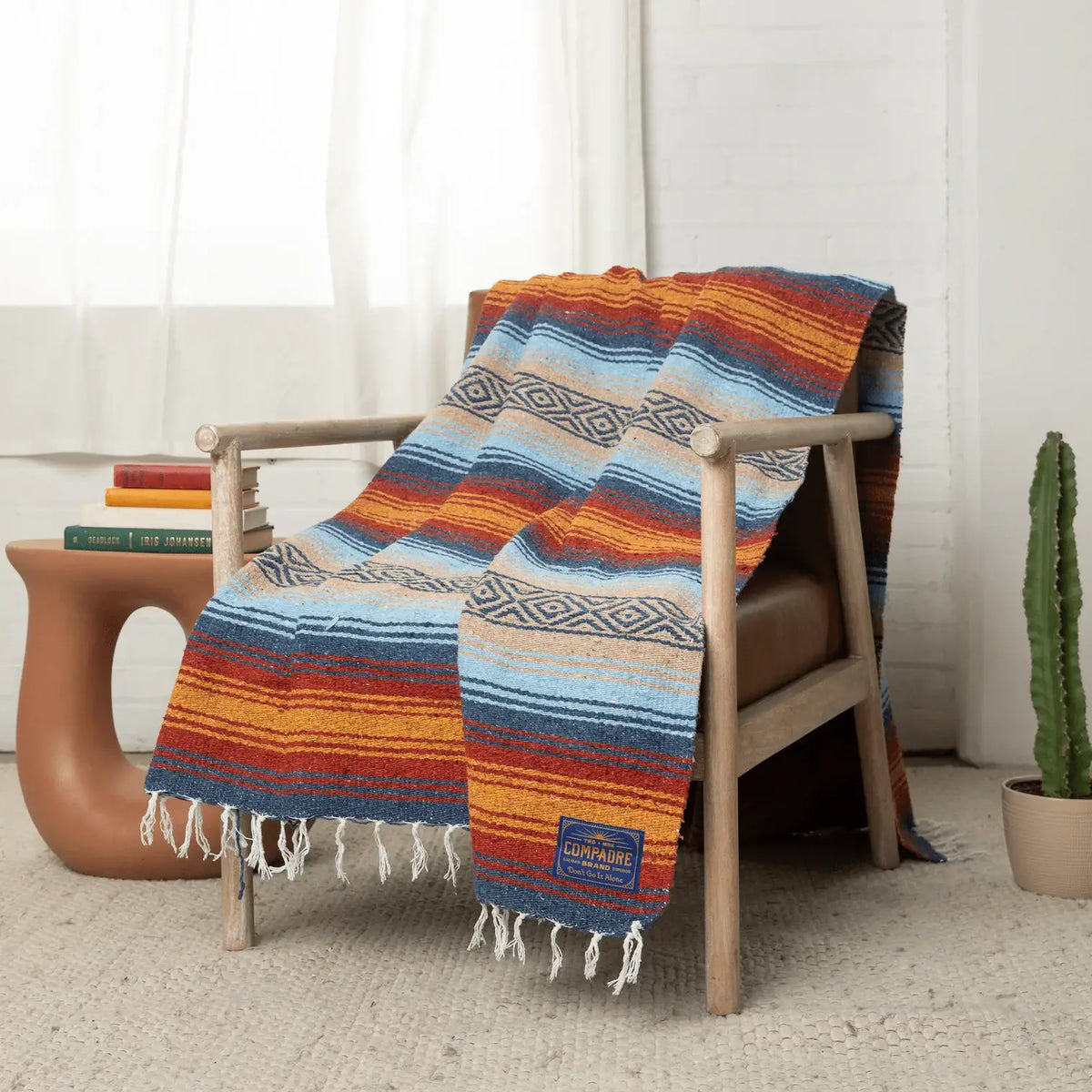 Light blue, orange and cream striped falsa blanket draped over a wooden armchair