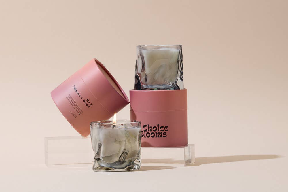 Smoky gray wavy glass candles stacked with pink boxes on clear risers