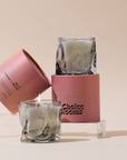 Smoky gray wavy glass candles stacked with pink boxes on clear risers