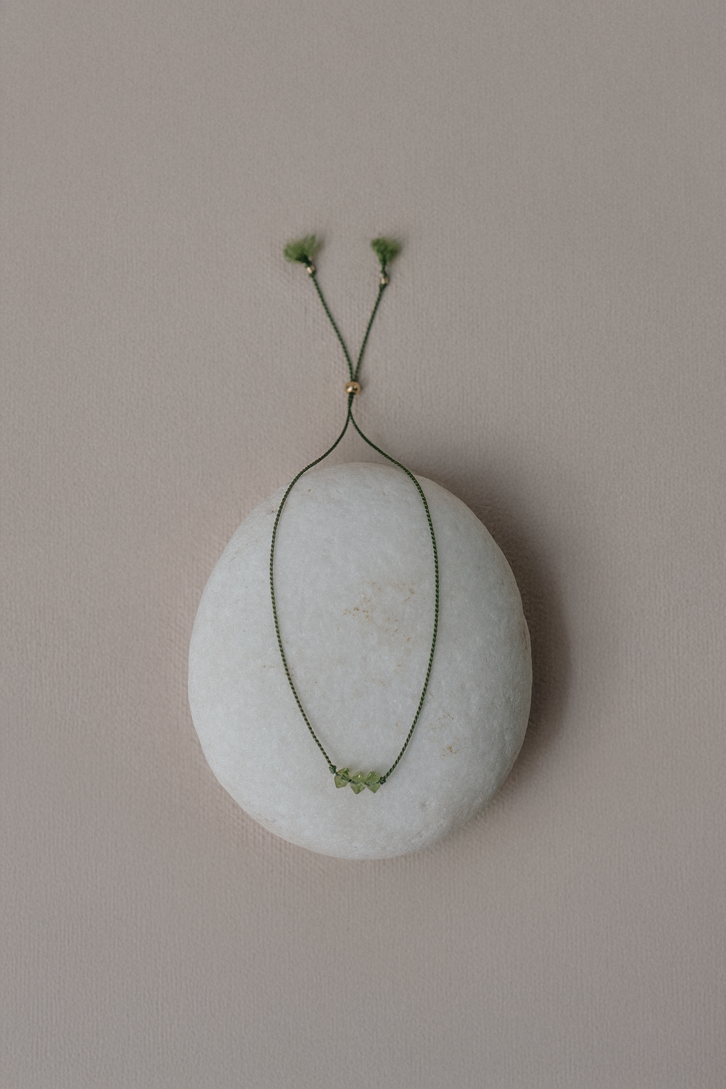 White stone with a green wire and small green flowers on a beige background