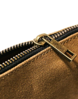 Close-up of a brass zipper pull on tan waxed canvas, slightly unzipped