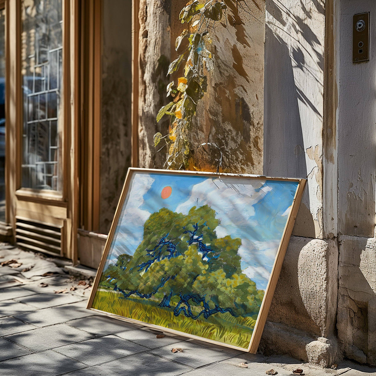 Framed live oak print leaning in a sunny doorway with tree shadows