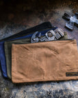 Waxed canvas zipper tool bags in tan, olive, navy and black with wrenches and a hammer on a rusty metal surface