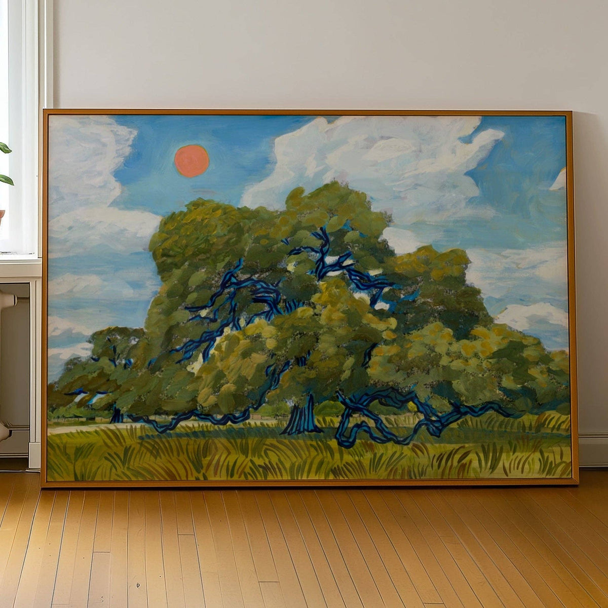 Live oak art print in a wood frame leaning against a white wall on a wood floor