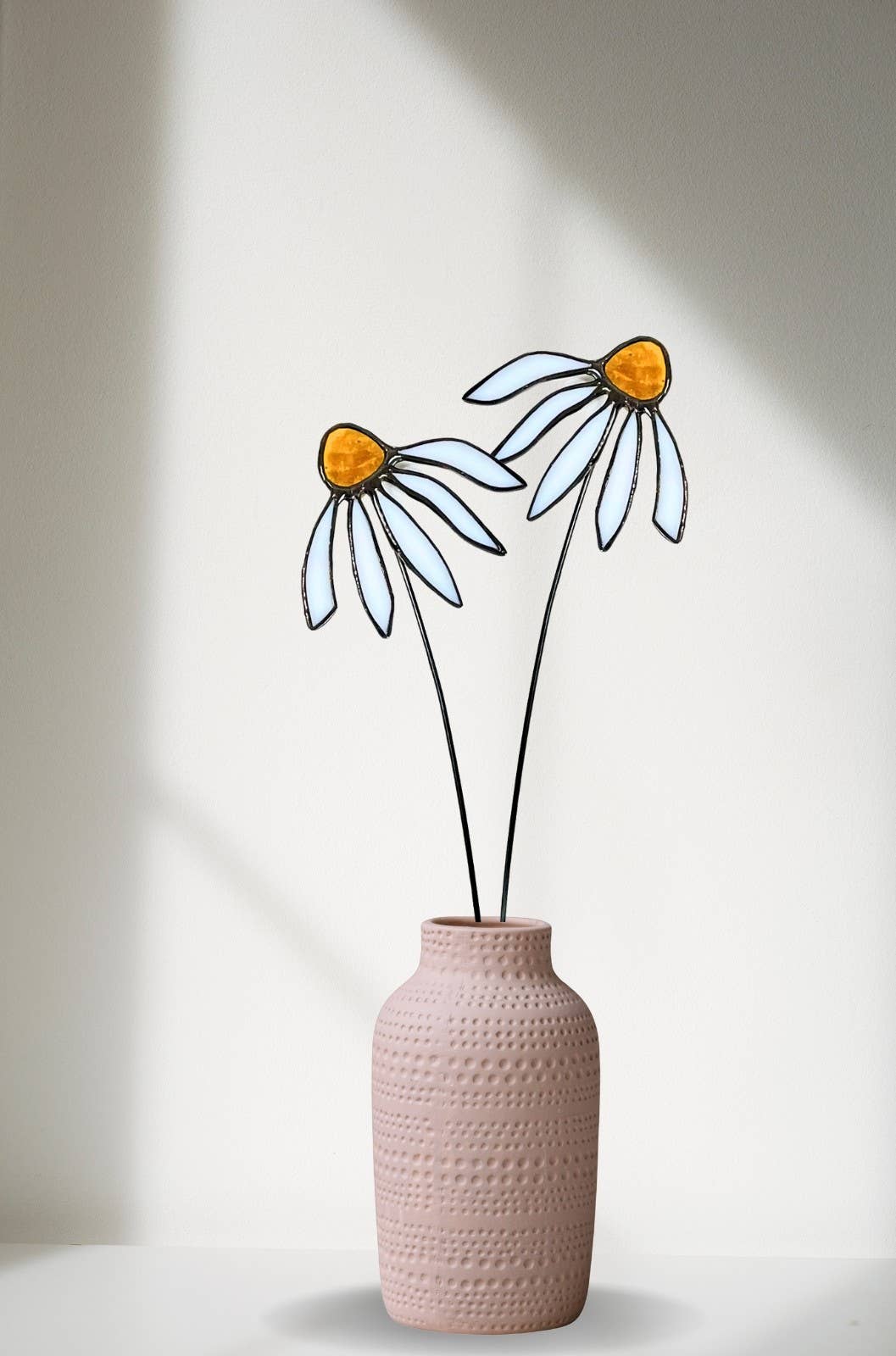 Two pale blue stained glass coneflowers with orange centers in a pink vase