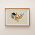 Framed print of a cowgirl in a hat floating on a yellow inner tube, on a white wall
