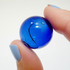 Fingers holding a cracked blue hand-blown glass sphere