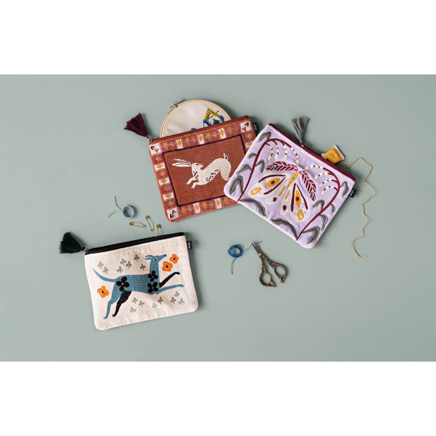 Three embroidered pouches with various designs on a light gray background