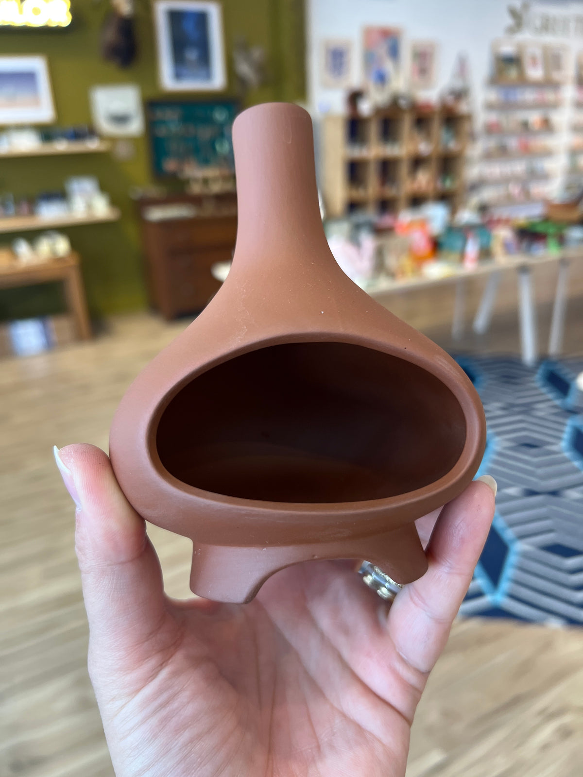 Hand holding a terracotta ceramic chiminea incense holder in the shop