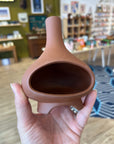 Hand holding a terracotta ceramic chiminea incense holder in the shop