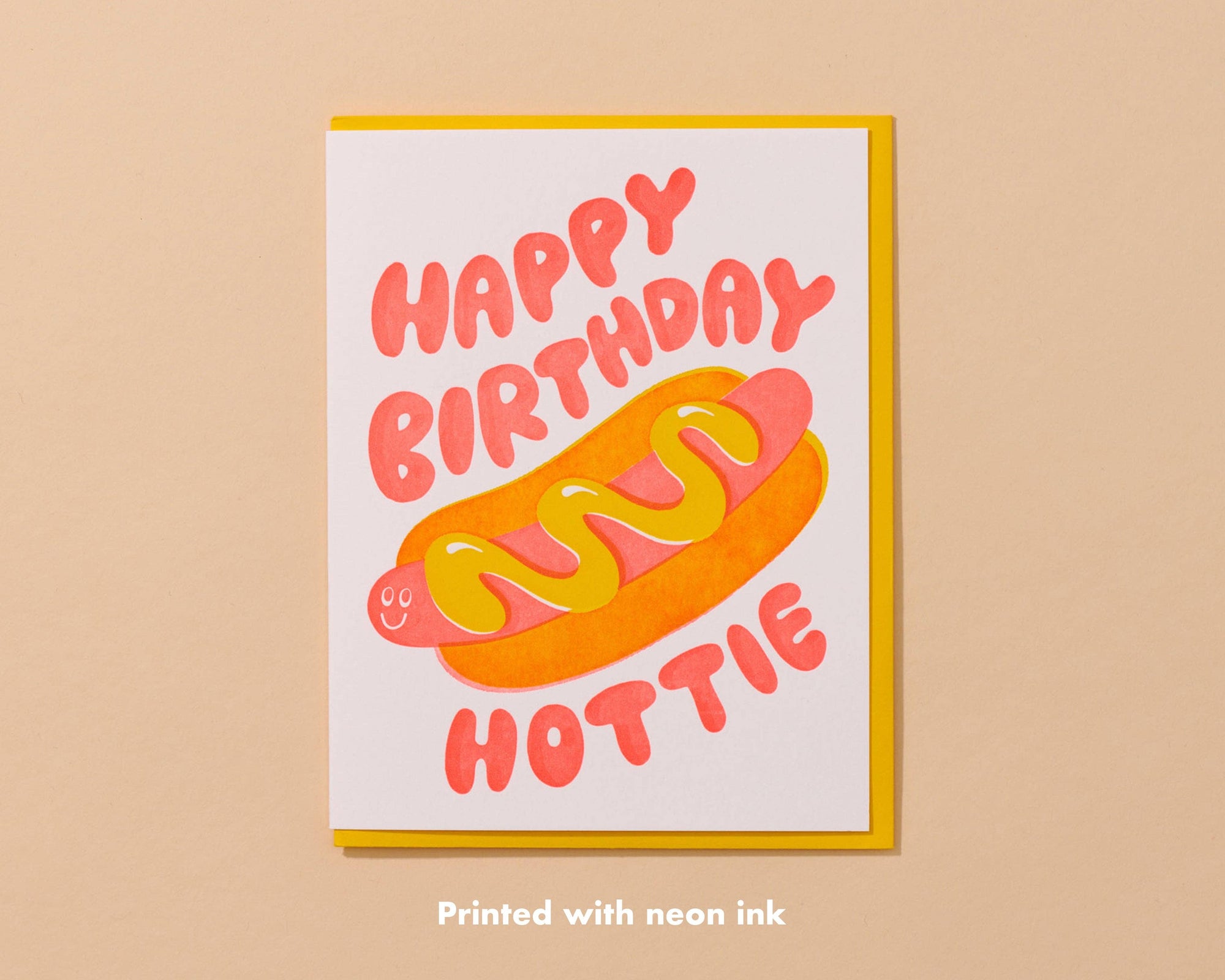 Send some sizzle with this adorable hot dog birthday card, where neon red and yellow inks cleverly overlap to form a tasty bun. The card playfully says, "Happy birthday, hottie," alongside a fun hot dog illustration.&nbsp;