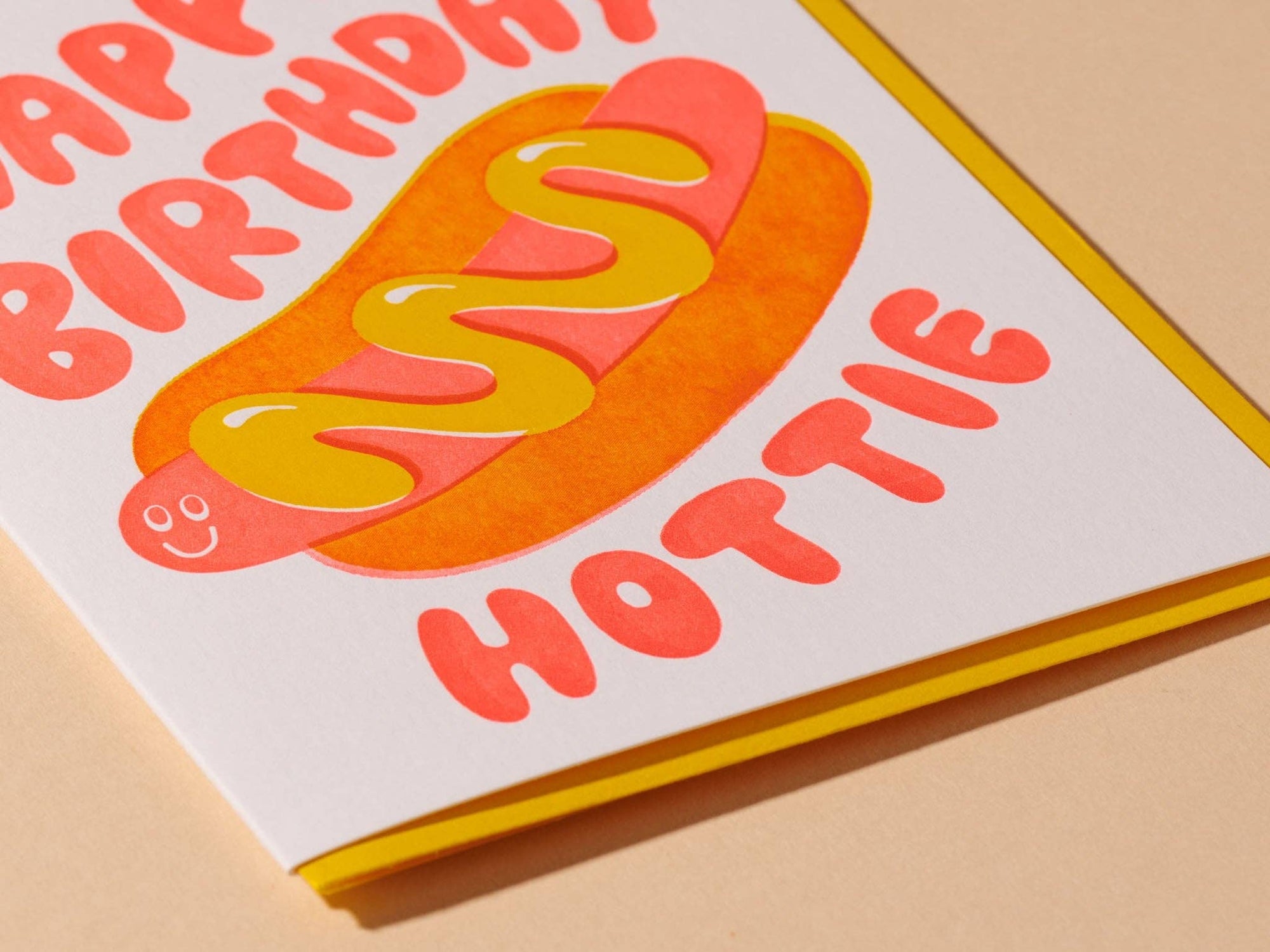 Send some sizzle with this adorable hot dog birthday card, where neon red and yellow inks cleverly overlap to form a tasty bun. The card playfully says, "Happy birthday, hottie," alongside a fun hot dog illustration.&nbsp;