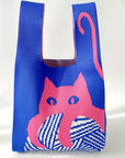 Blue knit shoulder bag with a pink cat on a ball of yarn, on a white backdrop