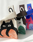 Three knit cat bags in cream, brown and blue, each with a different cat graphic