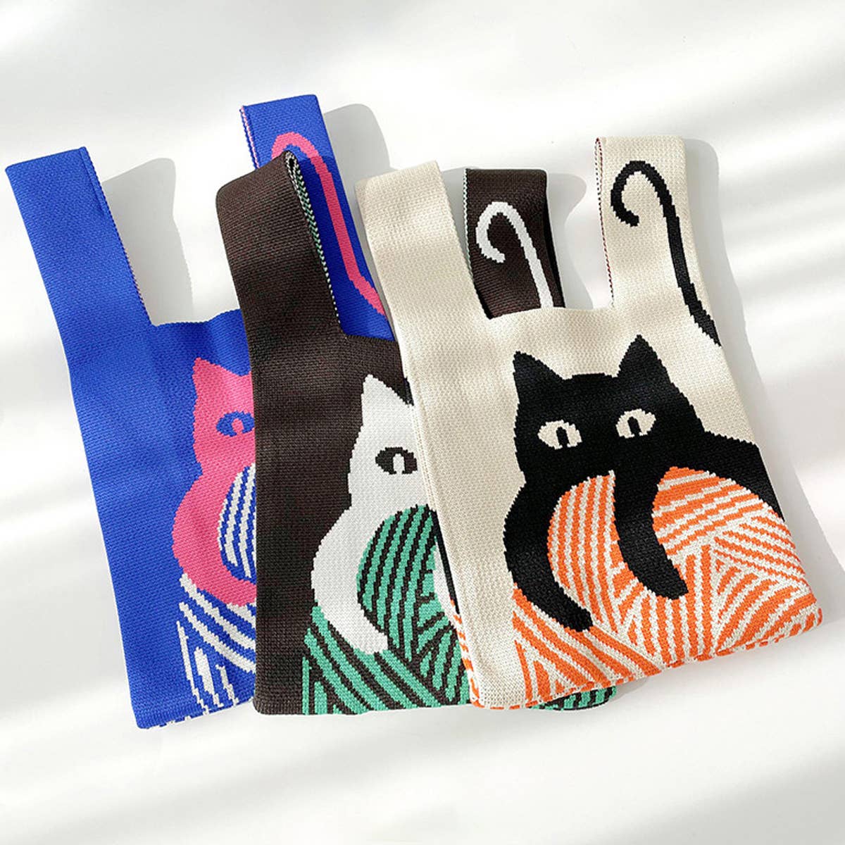 Cream, brown and blue knit cat shoulder bags lined up side by side