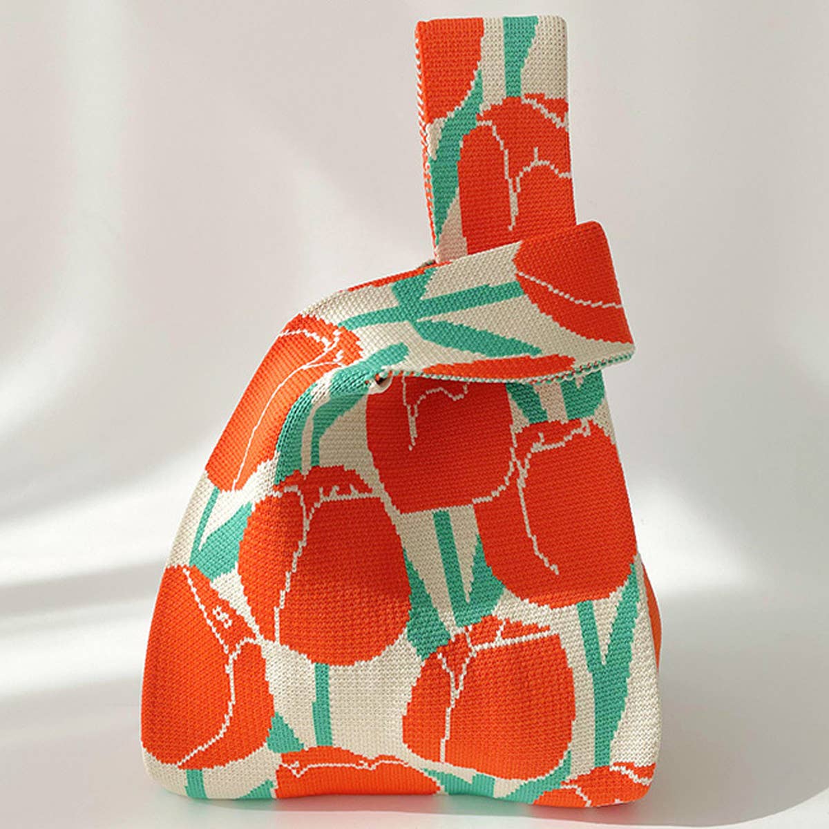 Knit shoulder bag with red-orange tulips and green stems on a cream background