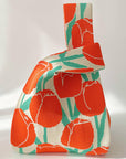 Knit shoulder bag with red-orange tulips and green stems on a cream background