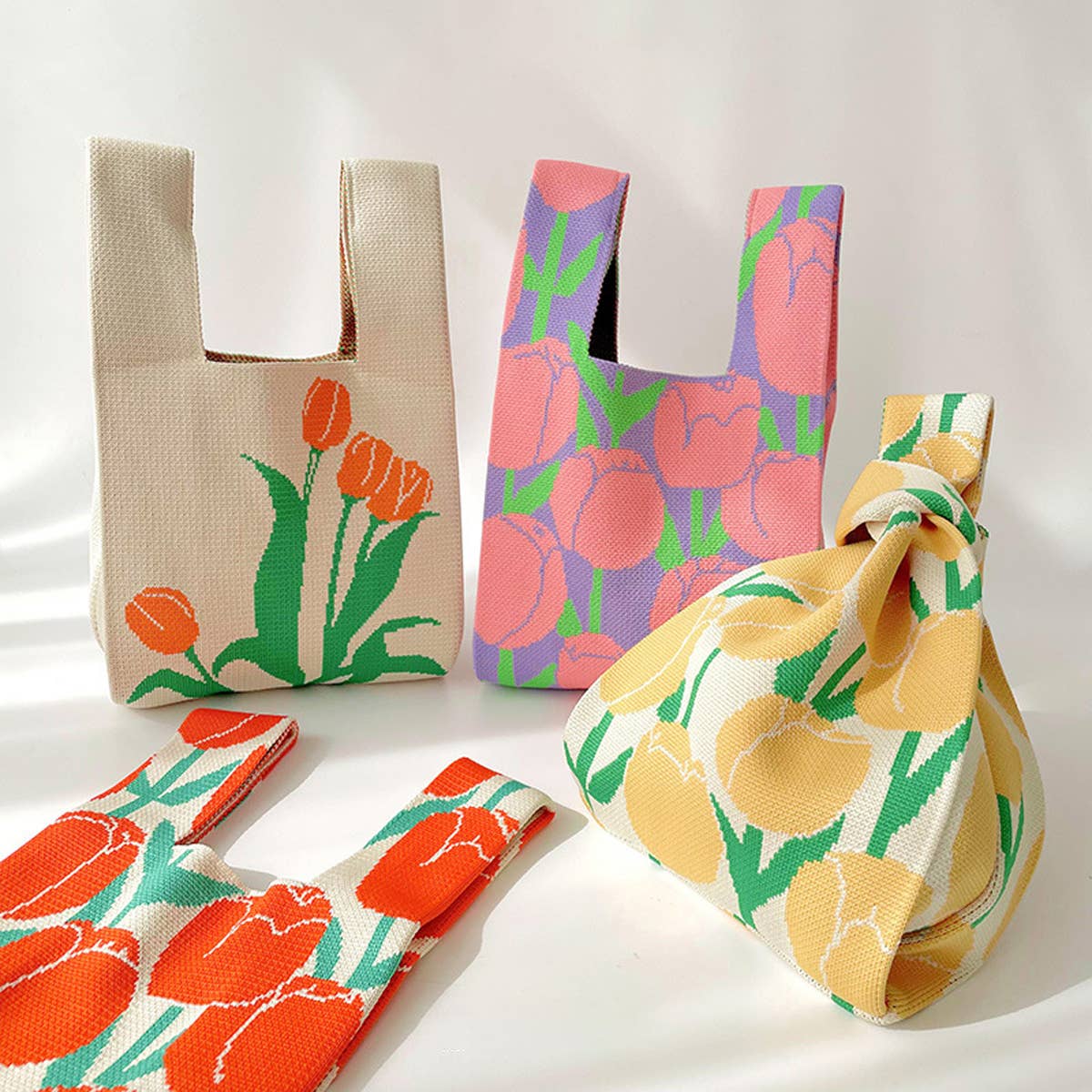 Cream knit bag with orange tulips and a pink floral knit bag tied in a knot