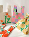 Cream knit bag with orange tulips and a pink floral knit bag tied in a knot