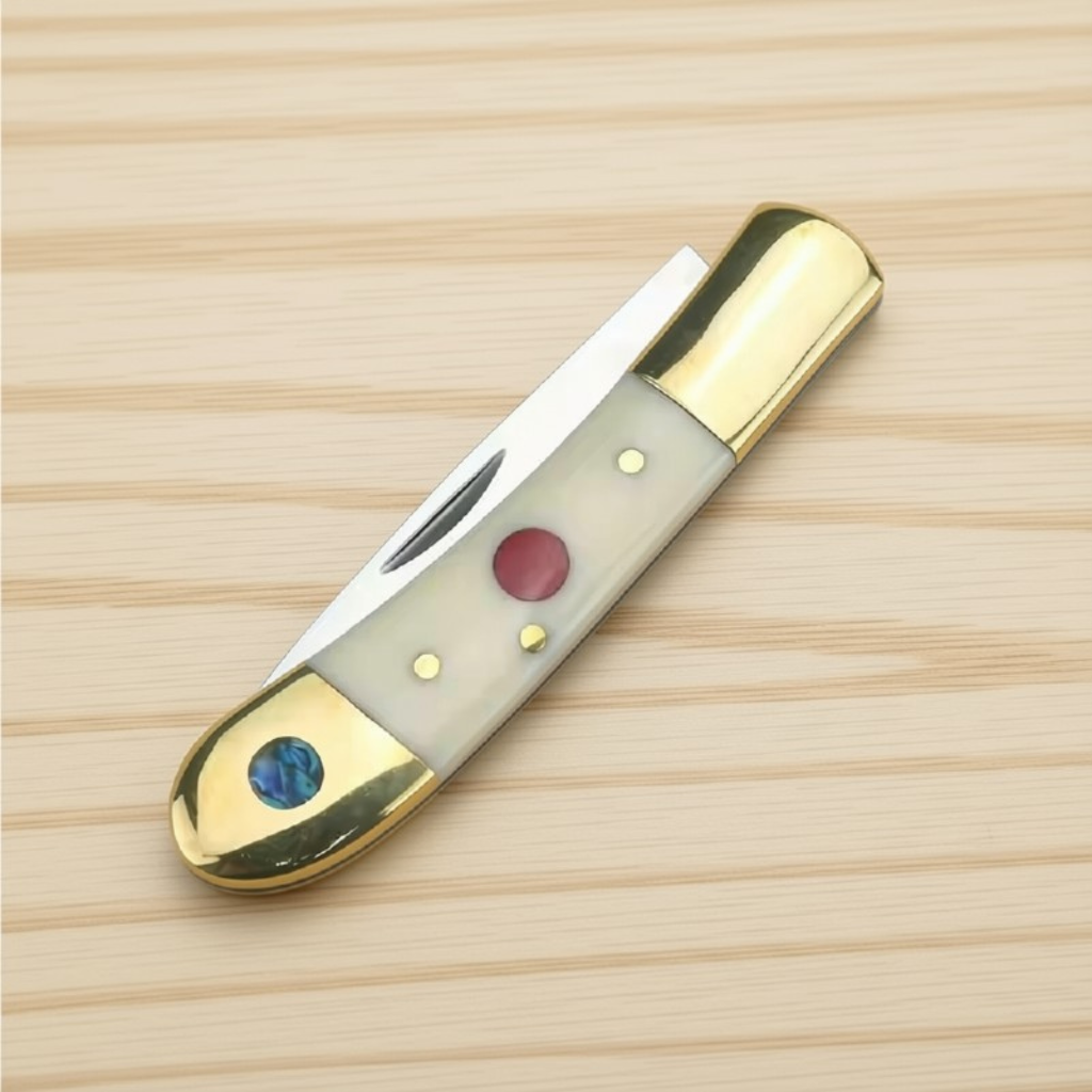 Bone-handled pocket knife, closed, with brass bolsters, a red inlay and an abalone disc on light wood