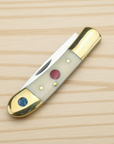 Bone-handled pocket knife, closed, with brass bolsters, a red inlay and an abalone disc on light wood