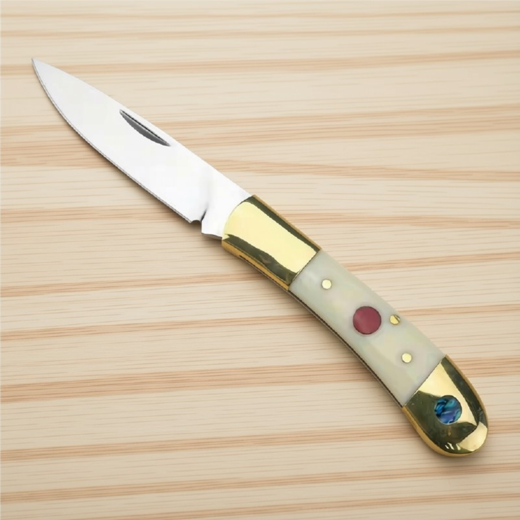 Bone-handled pocket knife, open, with brass bolsters, a red inlay and an abalone disc on light wood