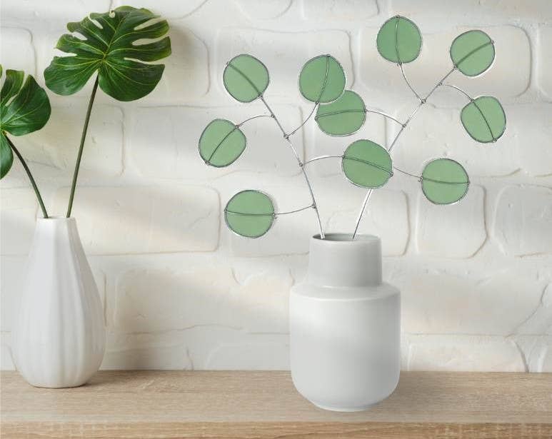Bring a pop of color and artistry to your home with this handcrafted stained glass silver dollar eucalyptus stem by Samara Designs Studio. This stem is made from beautiful celadon green stained glass, carefully cut and assembled by hand to create a lasting botanical accent that will never wilt or fade.